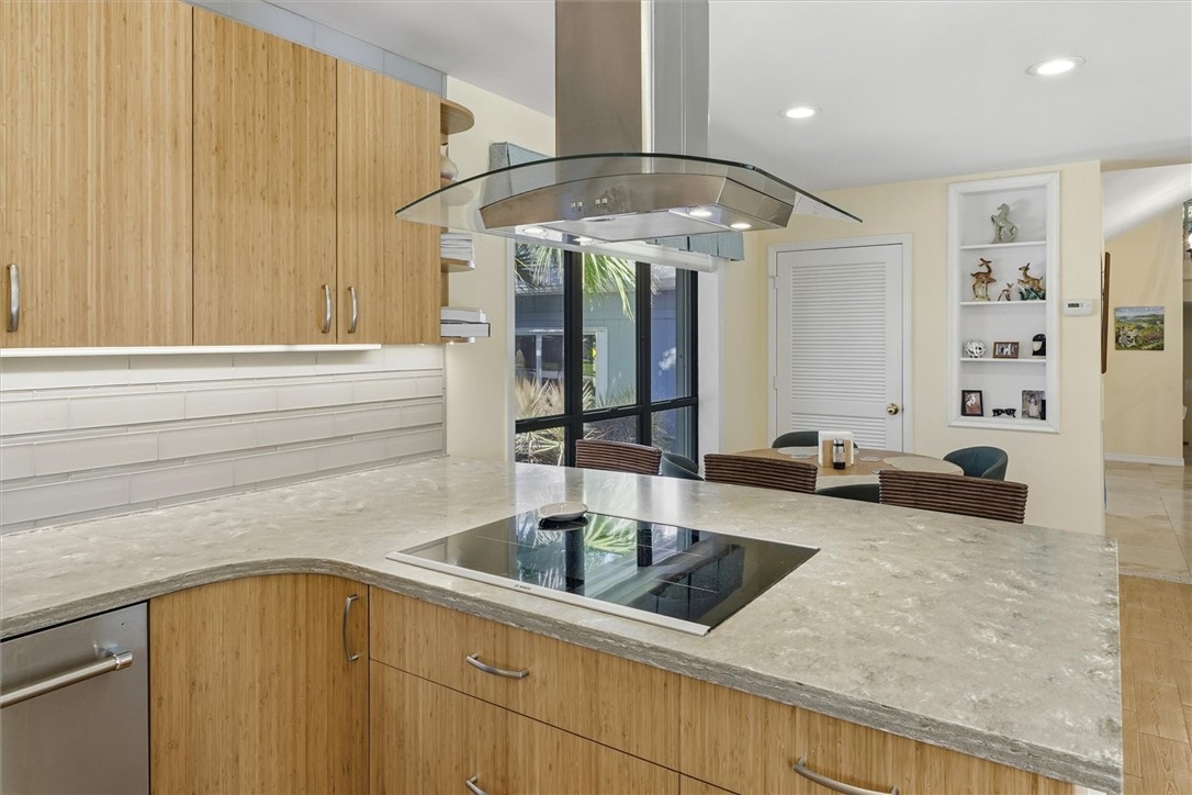 Kitchen featuring light stone counters, island ran