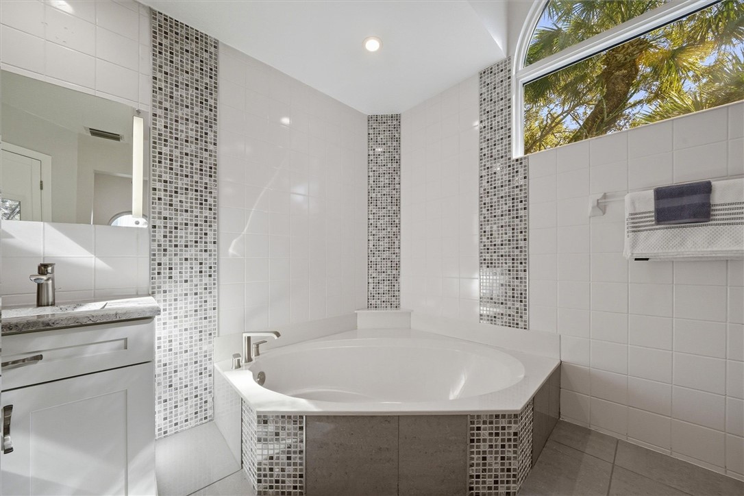 Full bathroom featuring tile walls, vanity, a gard