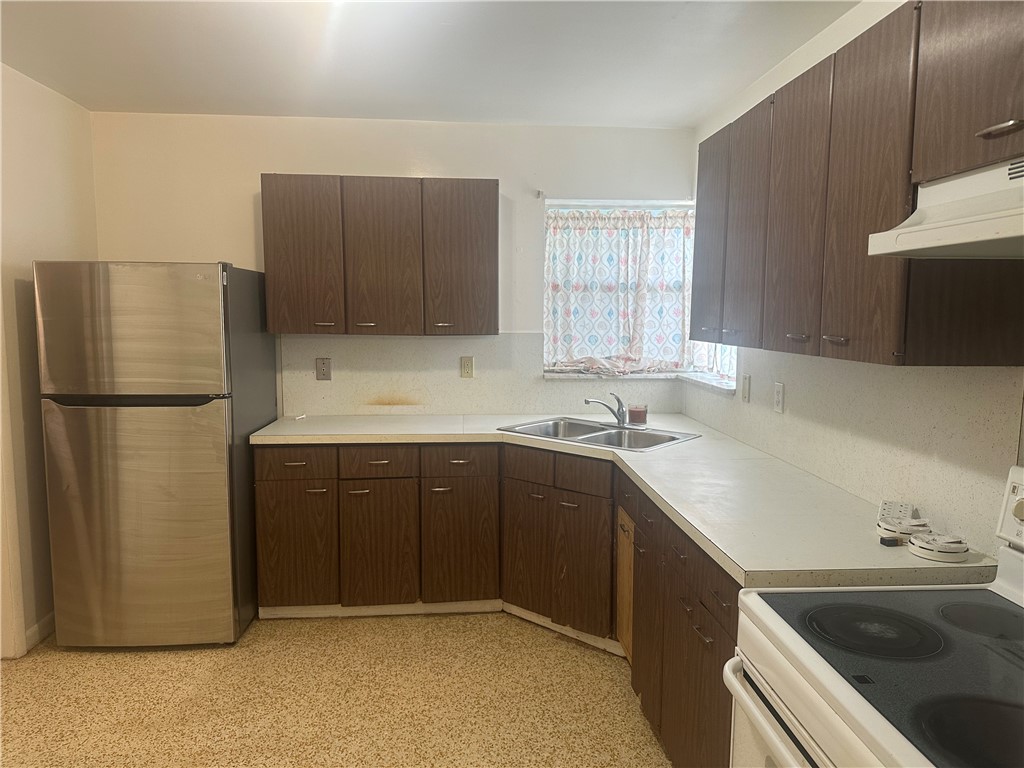 Kitchen with white electric range, dark wood finis
