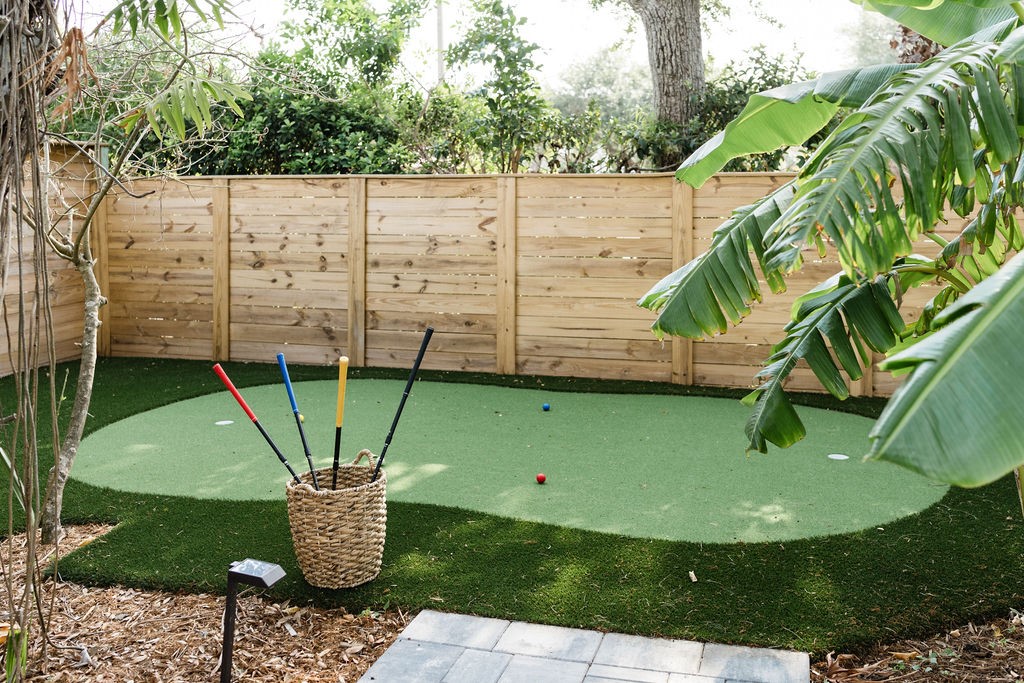 Backyard putting green framed by a horizontal wood