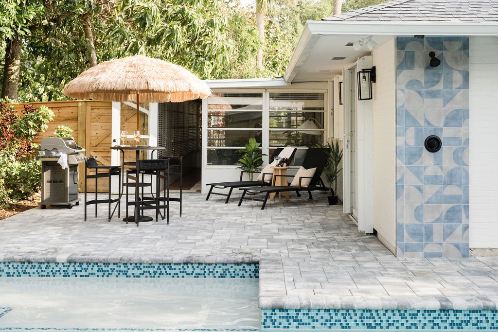 Paved patio area featuring a tiled pool edge, an o