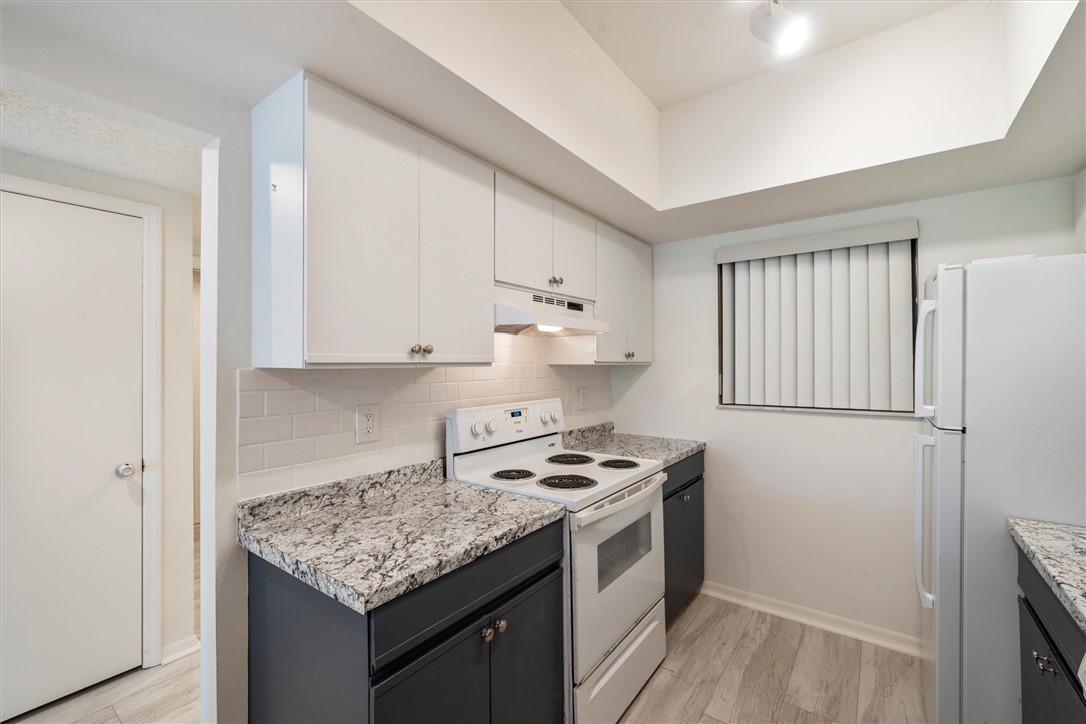 Kitchen with range, refrigerator and white cabinet